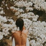 topless person standing near white petaled flowers