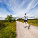 man running on road near grass field